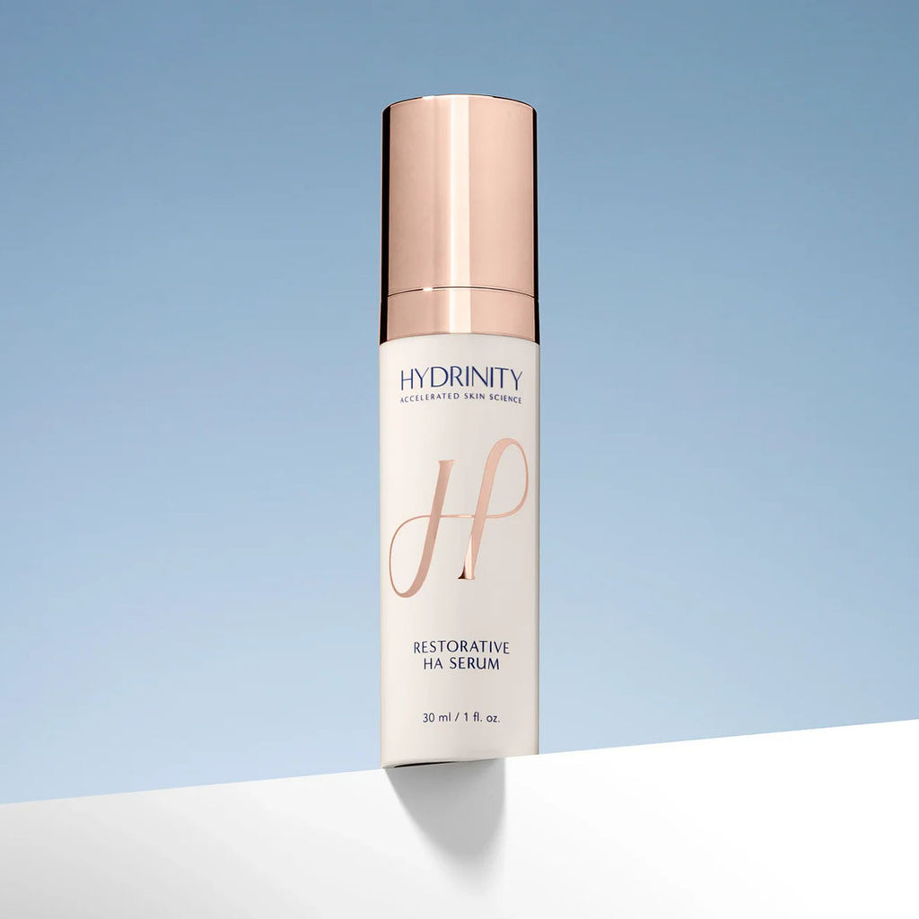 Hydrinity Restorative HA Serum in a white bottle with a rose gold pump cap.