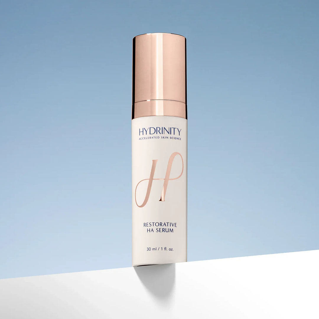 Hydrinity Restorative HA Serum in a white bottle with a rose gold pump cap.