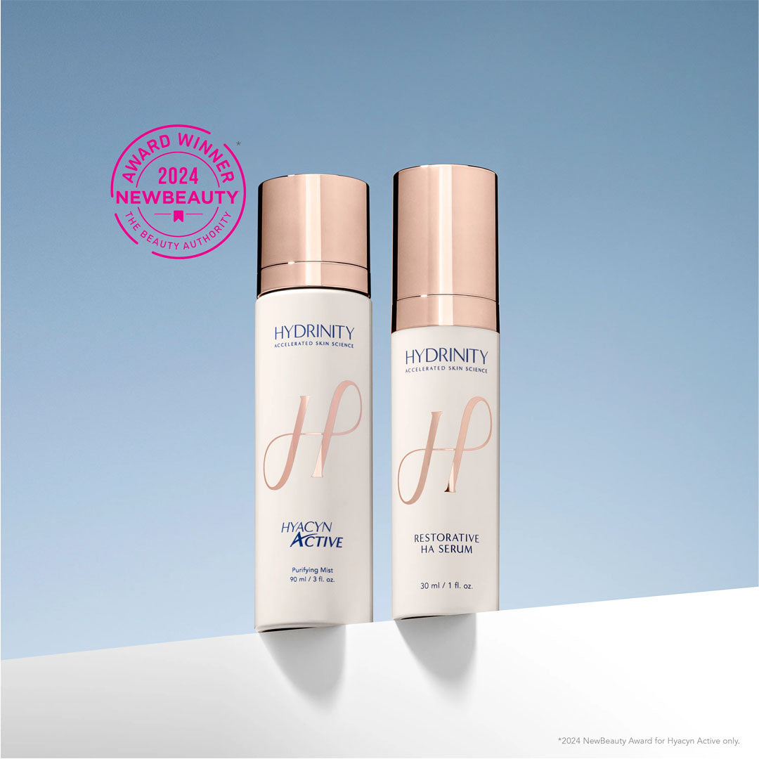 Two white Hydrinity bottles with rose gold caps: Hyacyn Active purifying mist and Restorative HA serum.