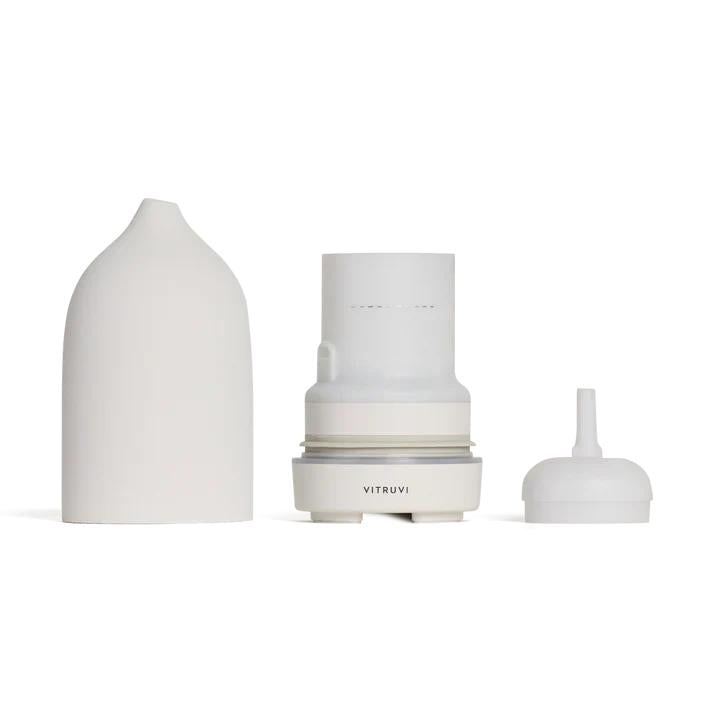 Vitruvi Stone Diffuser in white, disassembled to show its ceramic cover, internal mechanism, and small cap.