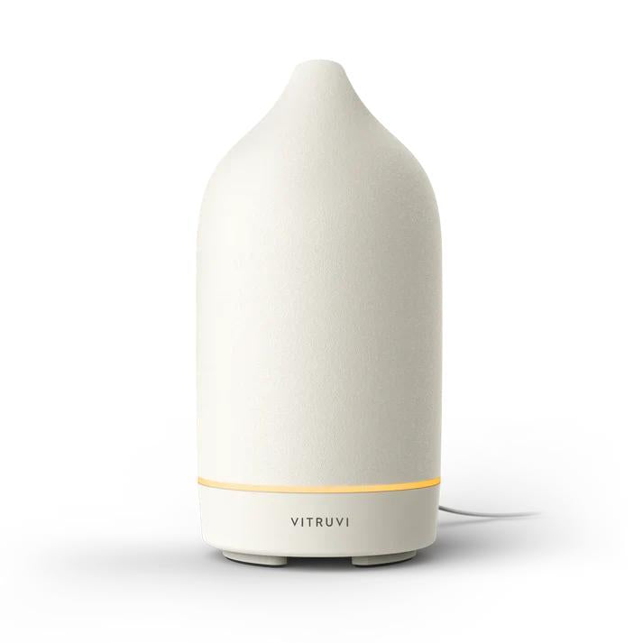 Vitruvi Stone Diffuser in cream, a sleek ceramic essential oil diffuser with a warm glow.