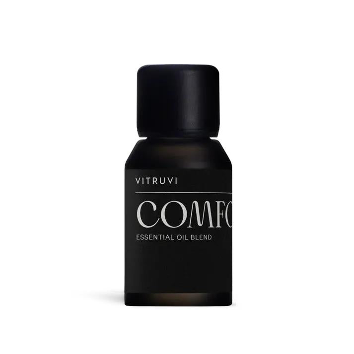 Vitruvi Comfort Diffuser Blend in a small, dark amber glass bottle with a matte black cap and label.