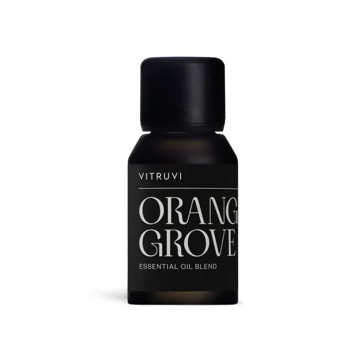 Small dark amber glass bottle of Vitruvi Orange Grove essential oil blend with a black cap.